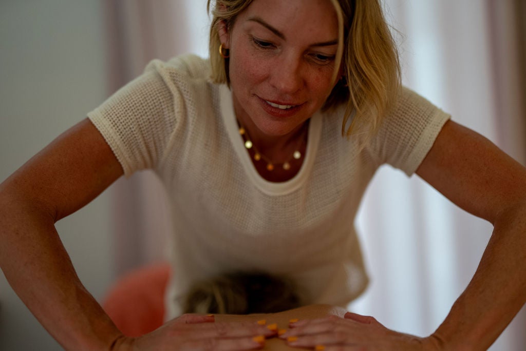 Jodie leaning in with both hands resting on a client's back